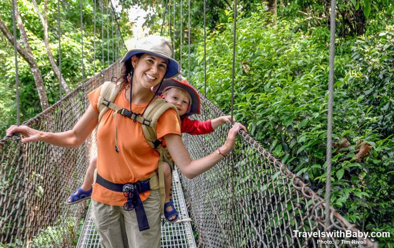 Family travel author and blogger Shelly Rivoli carries her toddler son across a hanging bridge in Costa Rica.