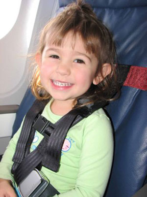 Little girl flying on airplane with CARES harness for air travel